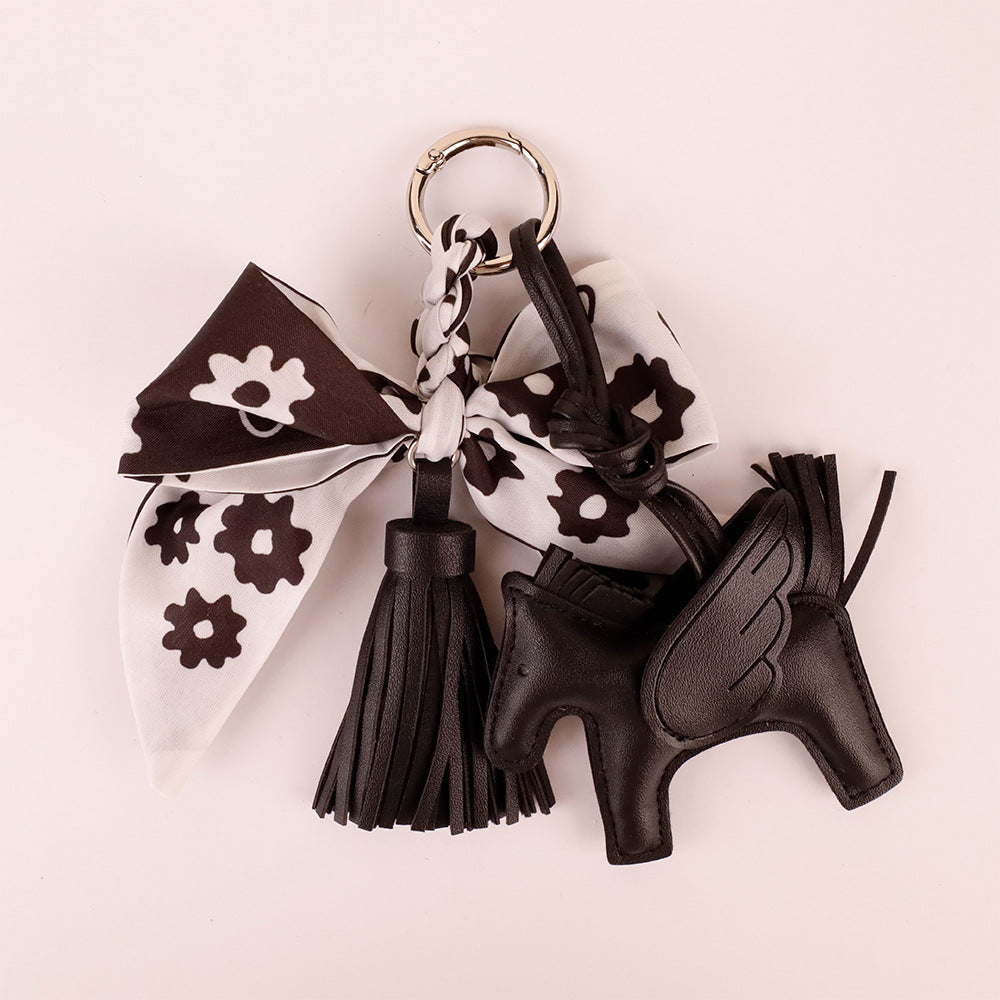 Cute black bow bag charm being attached to a daily crossbody purse