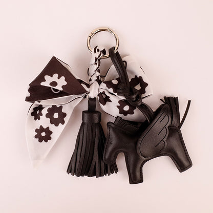 Cute black bow bag charm being attached to a daily crossbody purse