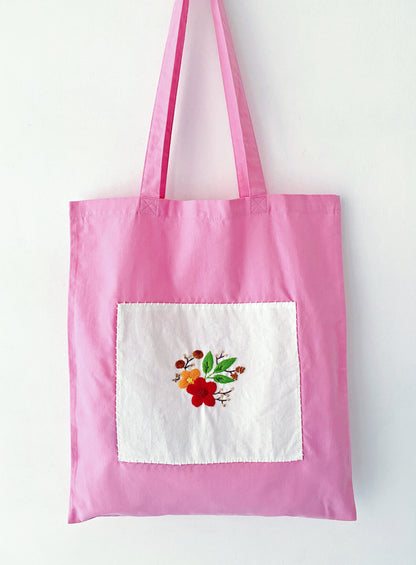 Close-up of hand-stitched floral embroidery on pink cotton tote