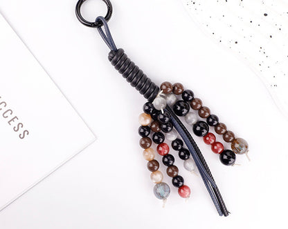 Detailed view of a decorative tassel charm featuring mixed gemstone beads and antique metal accents
