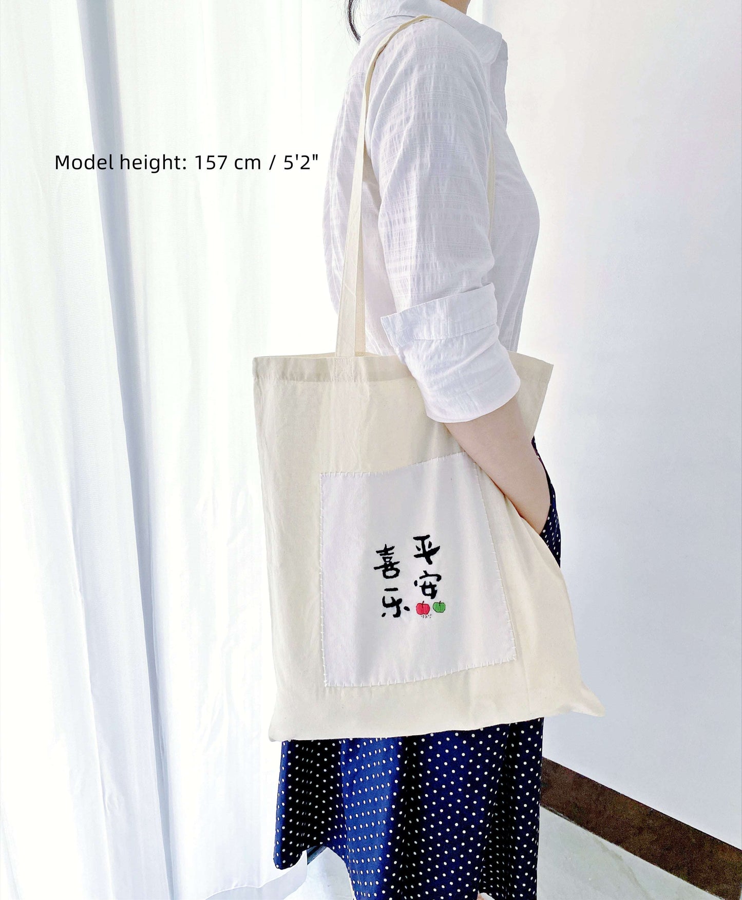 Minimalist outfit detail showing a hand-embroidered Chinese symbol on a slouchy cloth bag, wearable art for creatives.