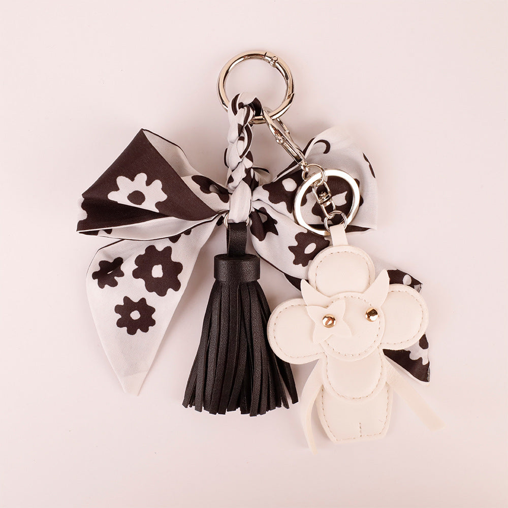 Elegant black and white tassel bow charm on a minimalist leather bag