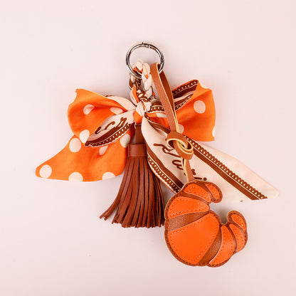 Scarf bow bag charm in orange with a flowing tassel