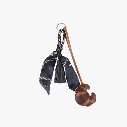 Croissant-shaped accessory hanging from a leather handbag
