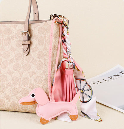 Luxury leather dachshund keychain attached to a leather crossbody bag