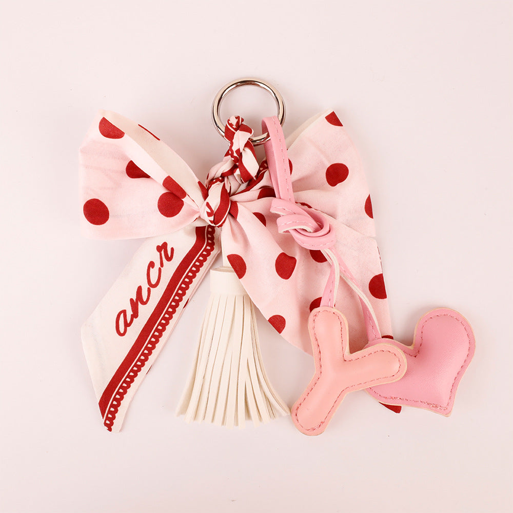 Pink tassel charm displayed beside a handbag