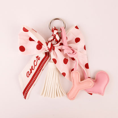 Pink tassel charm displayed beside a handbag