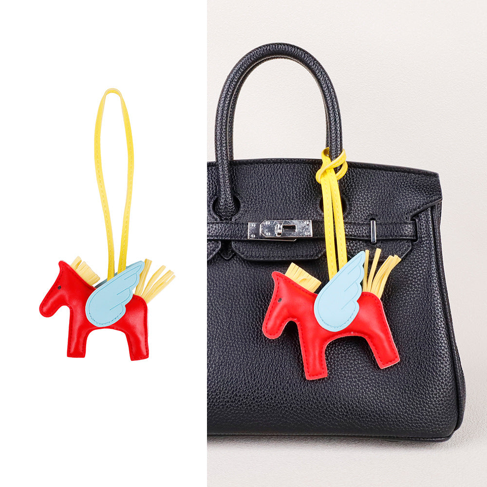 Modern equestrian inspired charm attached to a structured satchel bag handle