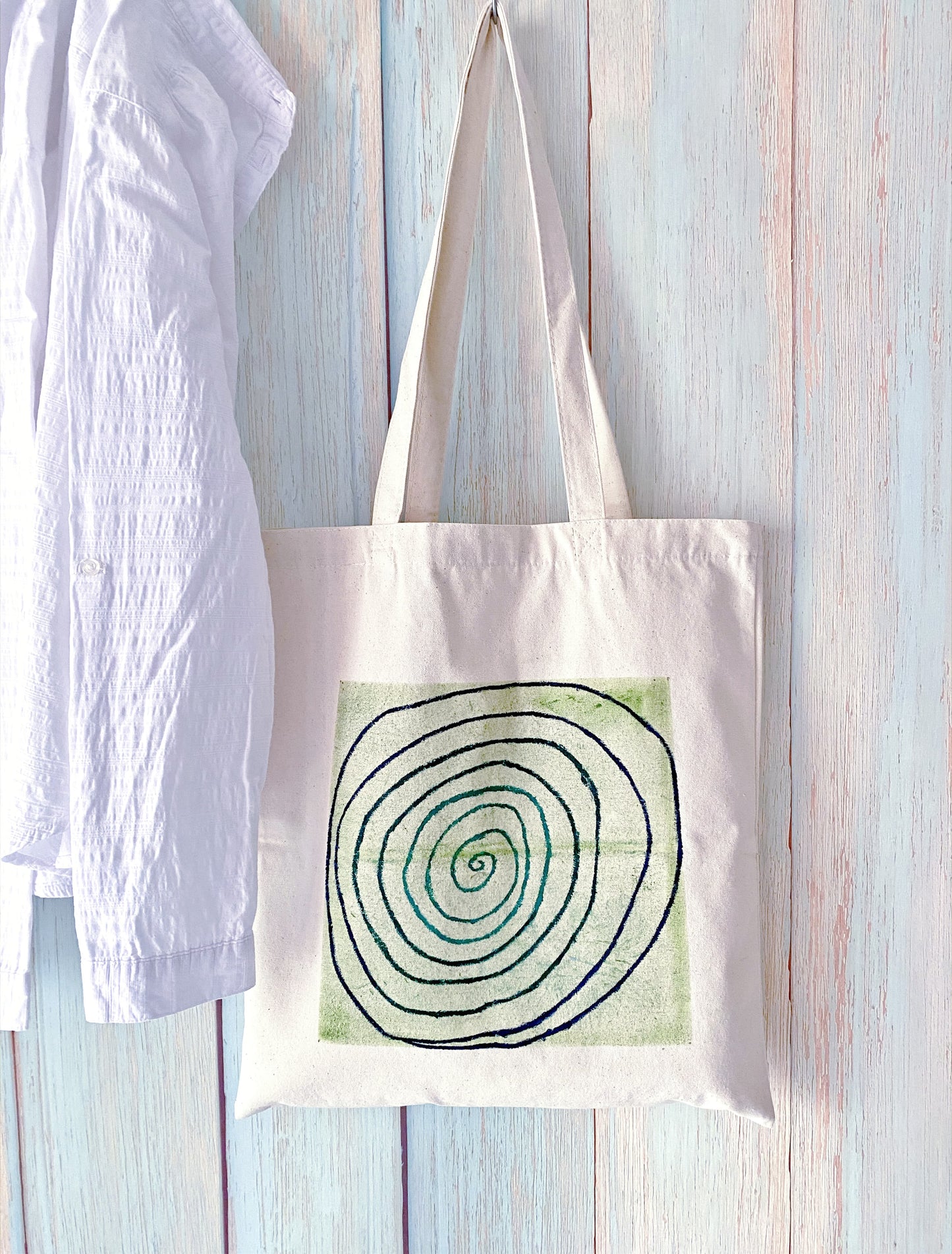 A minimalist tote bag resting on a cafe table next to a steaming latte.