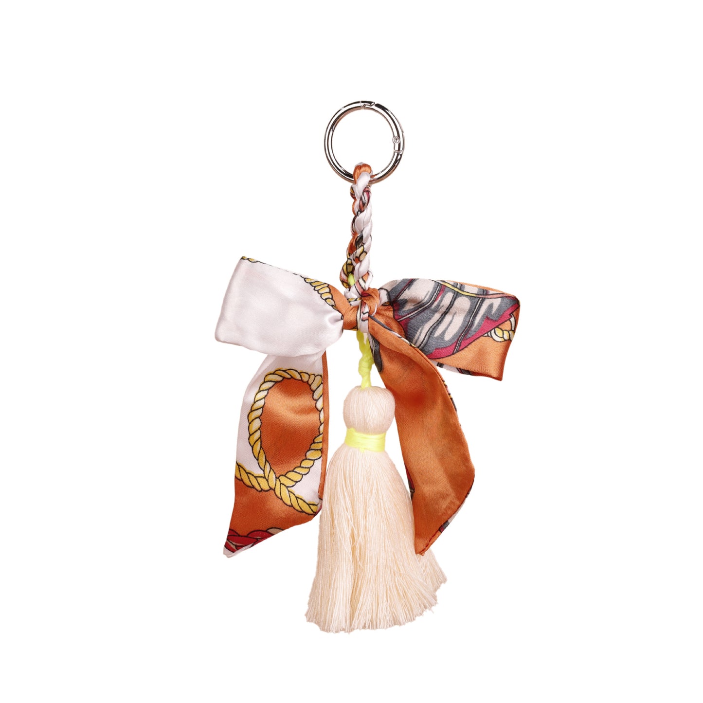 Soft silk scarf charm with tassel dangling from a designer clutch