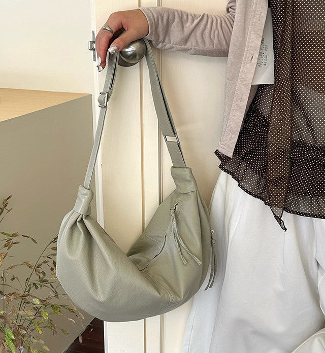 Crescent shoulder bag for carrying travel necessities.