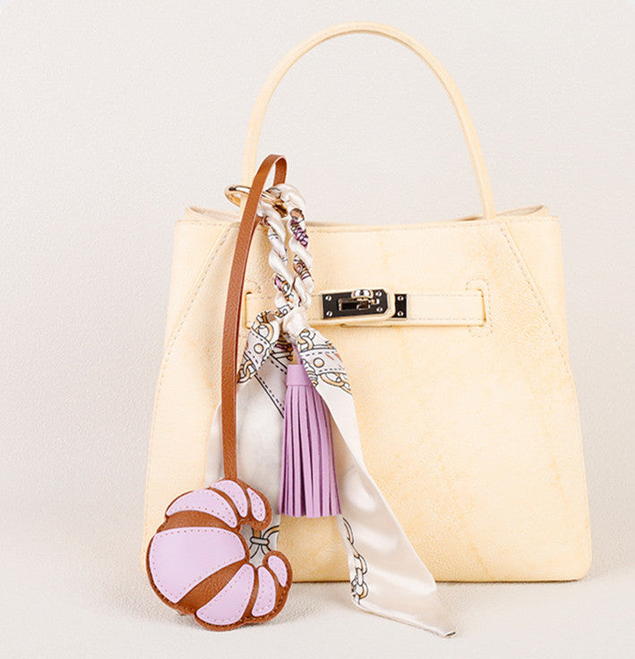 Small scarf accent attached to a structured shoulder bag