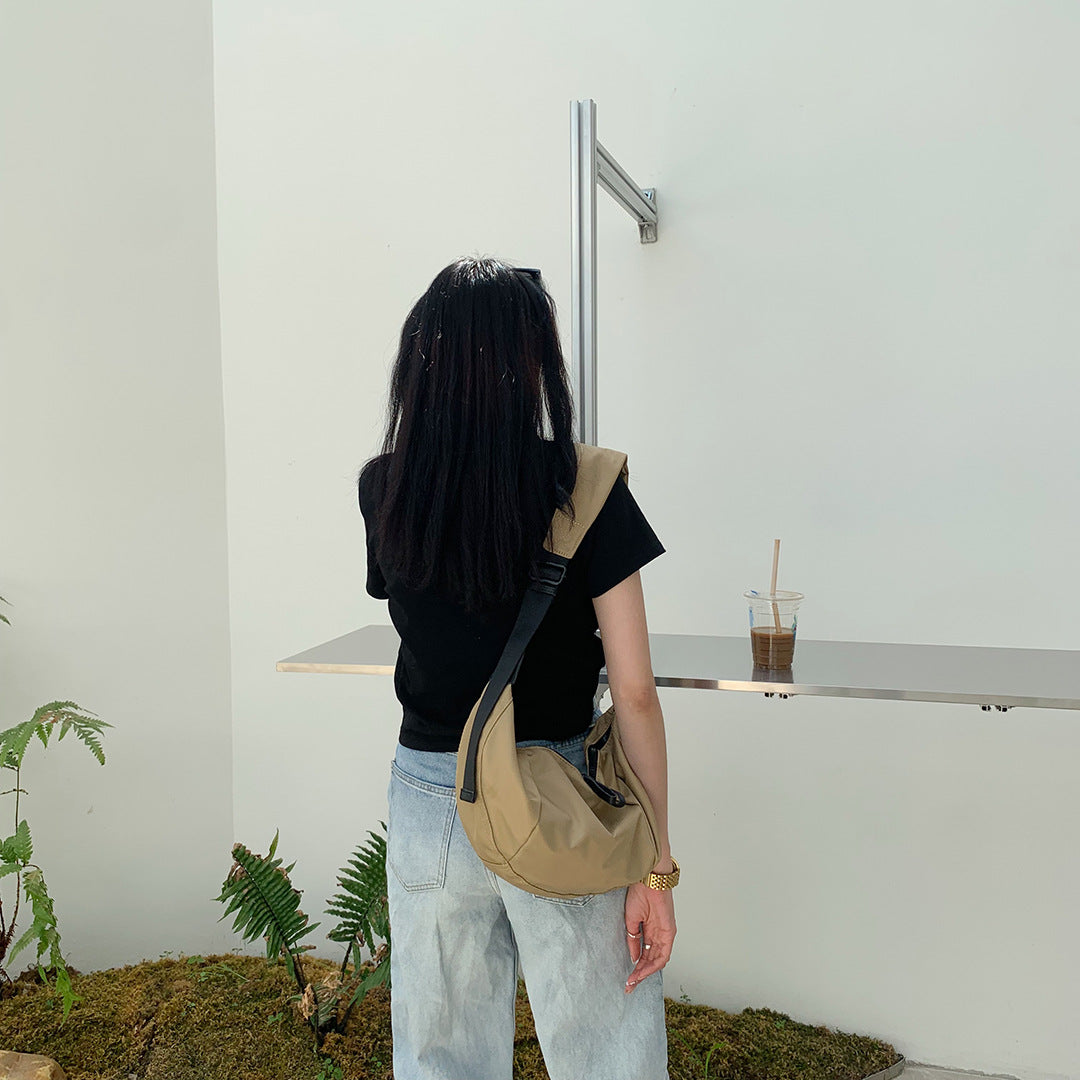 Women's curved sling bag worn across the chest for hands-free travel