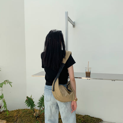 Women's curved sling bag worn across the chest for hands-free travel
