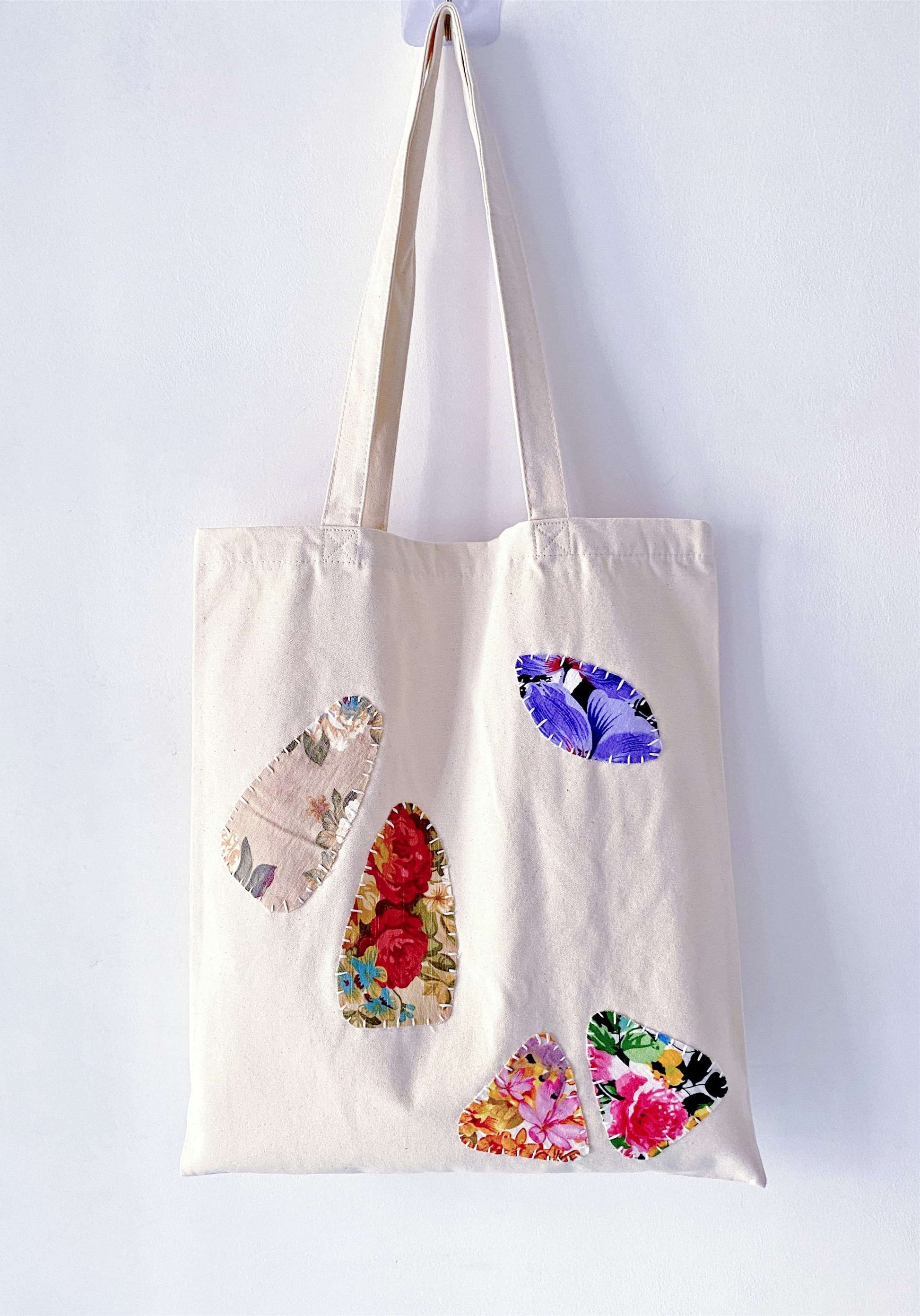 A versatile foldable bag being unrolled to hold a fresh loaf of sourdough and flowers.