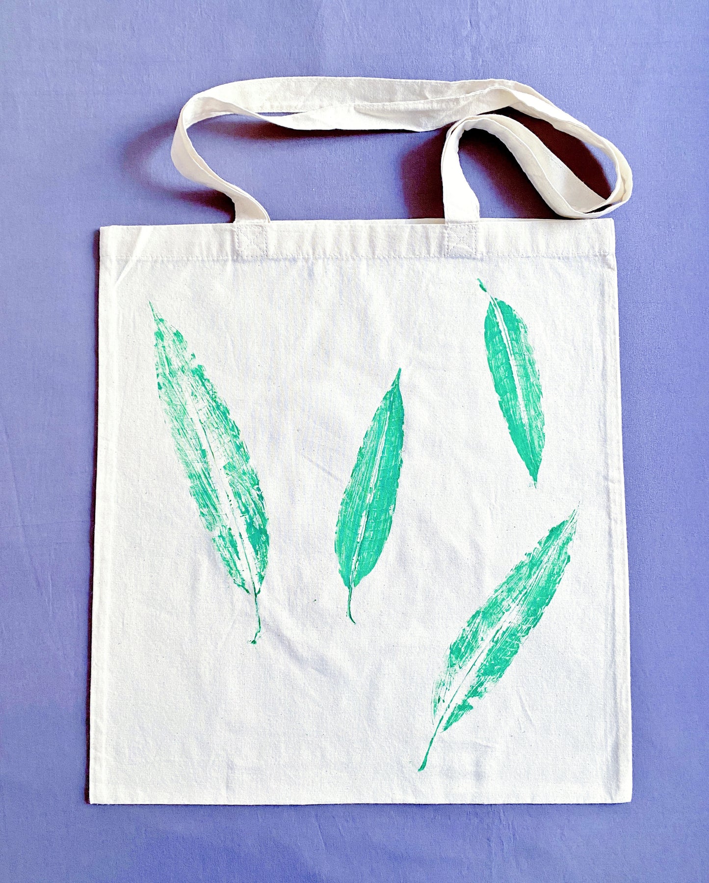 A perfect gift for eco-conscious friends, this cotton tote with hand-printed leaf design is both stylish and sustainable.