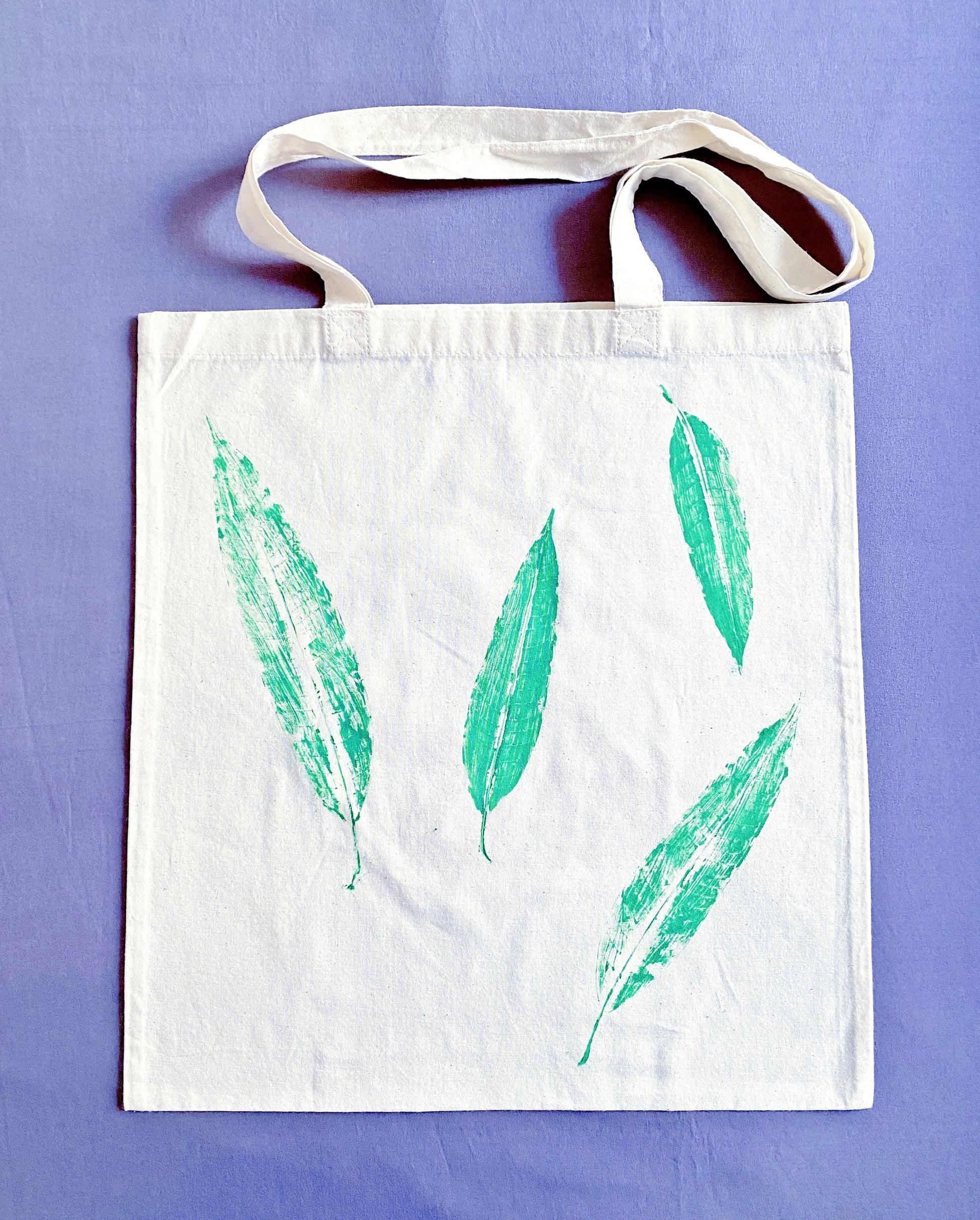A perfect gift for eco-conscious friends, this cotton tote with hand-printed leaf design is both stylish and sustainable.
