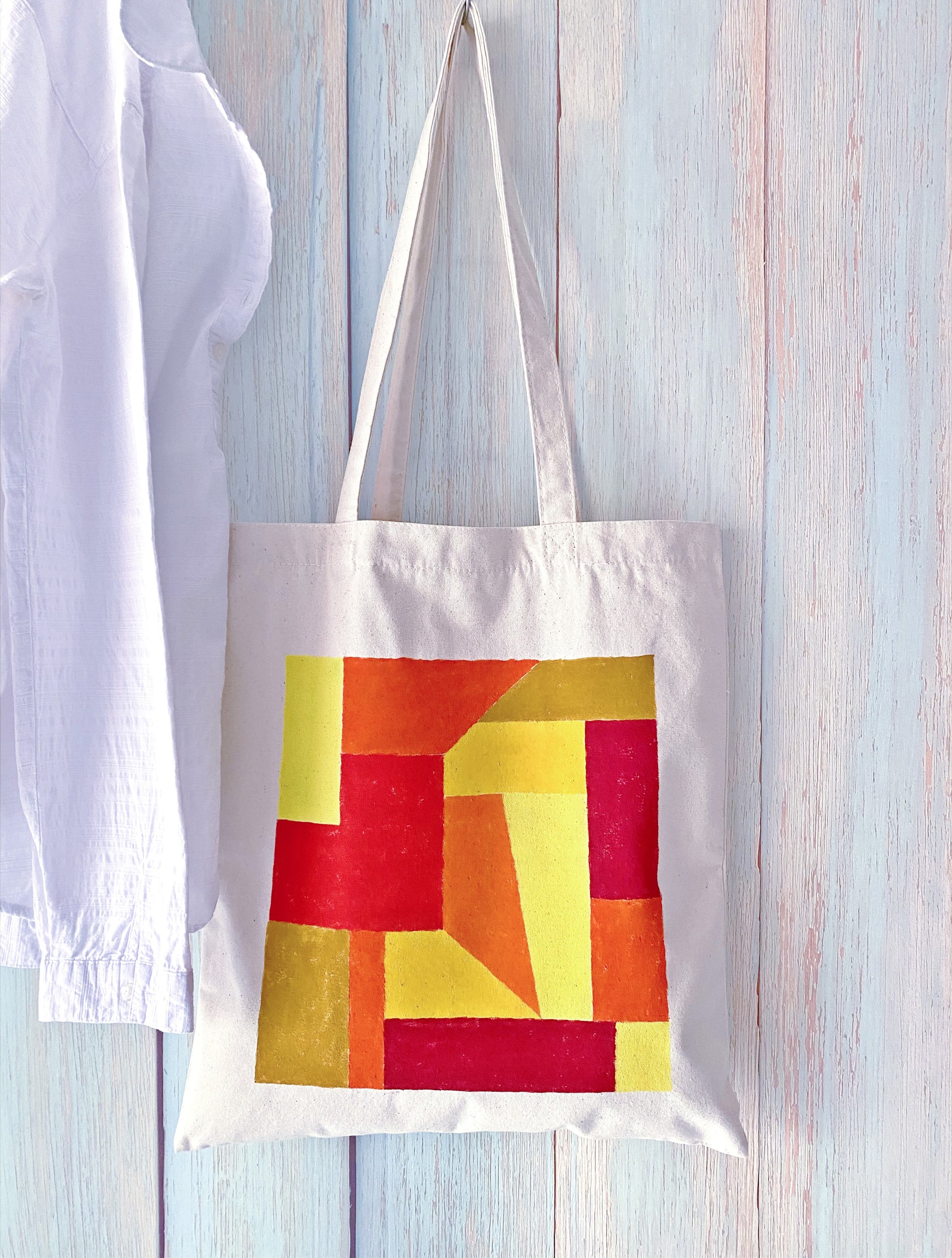 A relaxed-fit tote bag resting on a cafe chair next to a latte.