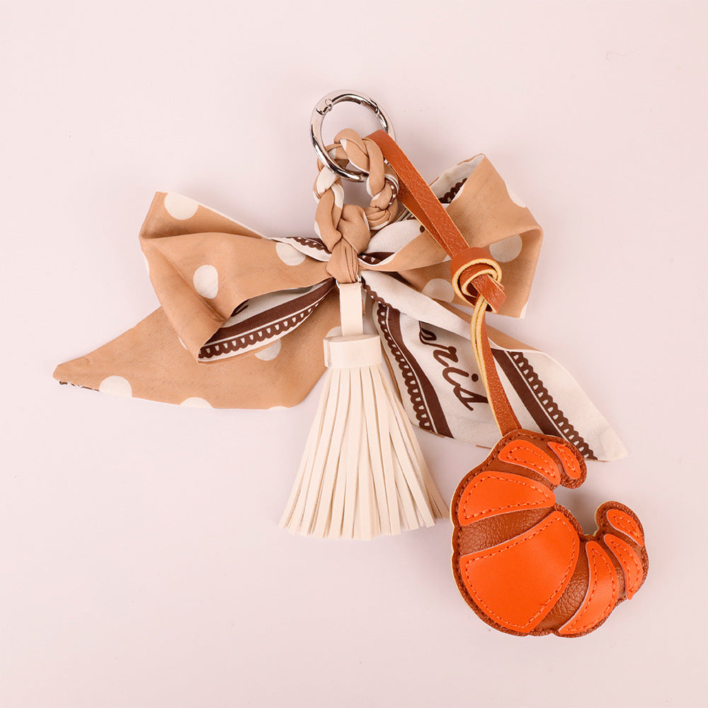 Small French-style bag accessory with tassel detail