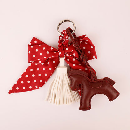 Scarf-style red bow ornament attached to a backpack zipper