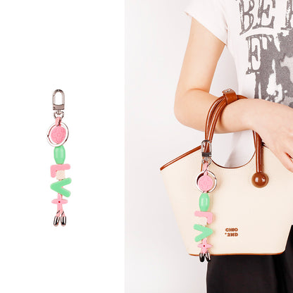 Vibrant letter pendant hanging from woven beach tote
