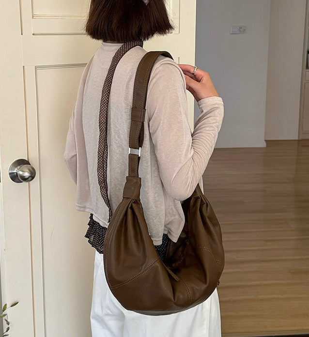 Women's curved bag carried over the shoulder while shopping.