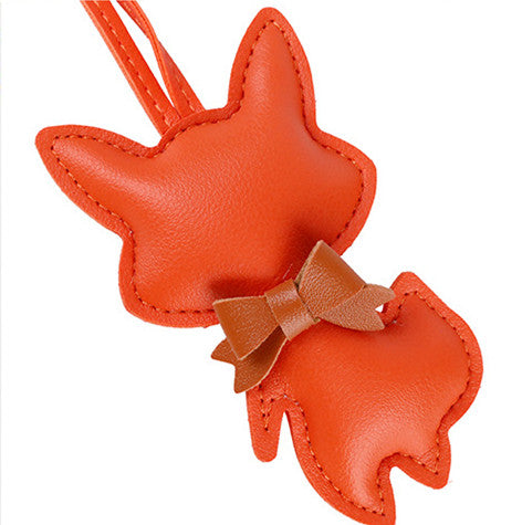Scarf-wrapped fox charm adding character to a simple handbag