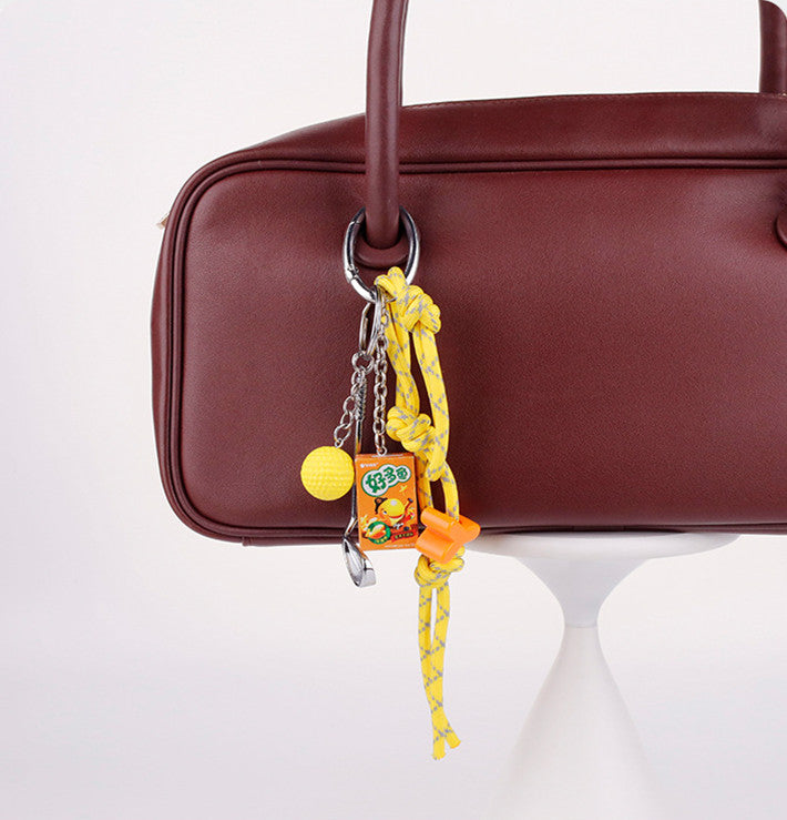 Bright yellow handmade charm hanging on a modern minimalist crossbody purse